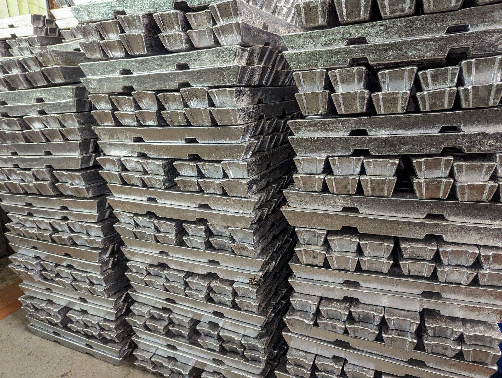 Several stacks of aluminum bars arranged in a warehouse