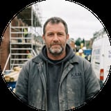 Middle-aged man wearing dark K&M Services jacket on construction site