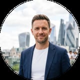 Man in navy blazer smiling with London skyline in background
